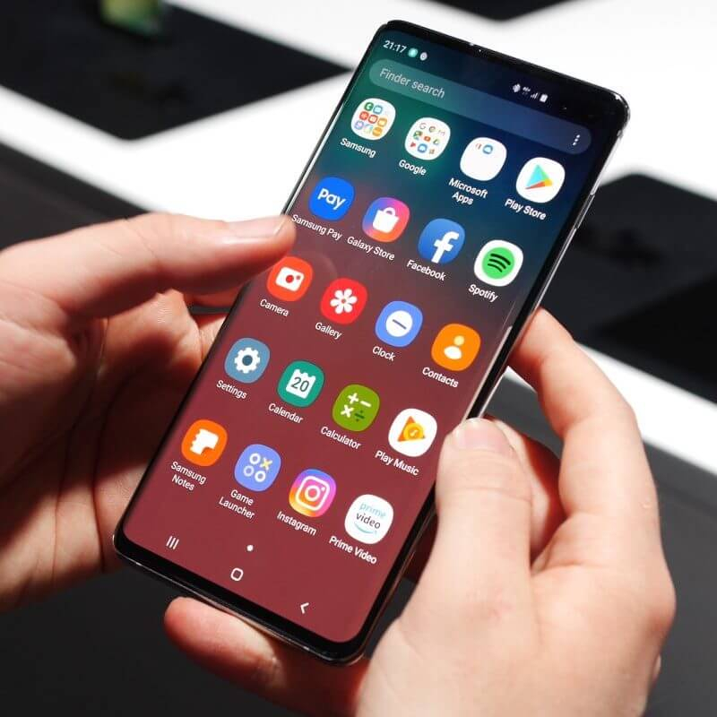 Samsung Galaxy S10+ in two hands by computer