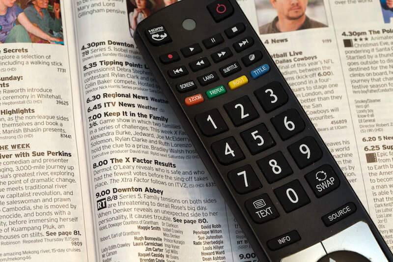 close-up of a television remote control lying on a tv guide