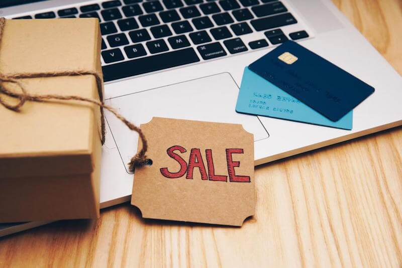 sale tag online shopping wih a gift and credit cards lying on a laptop