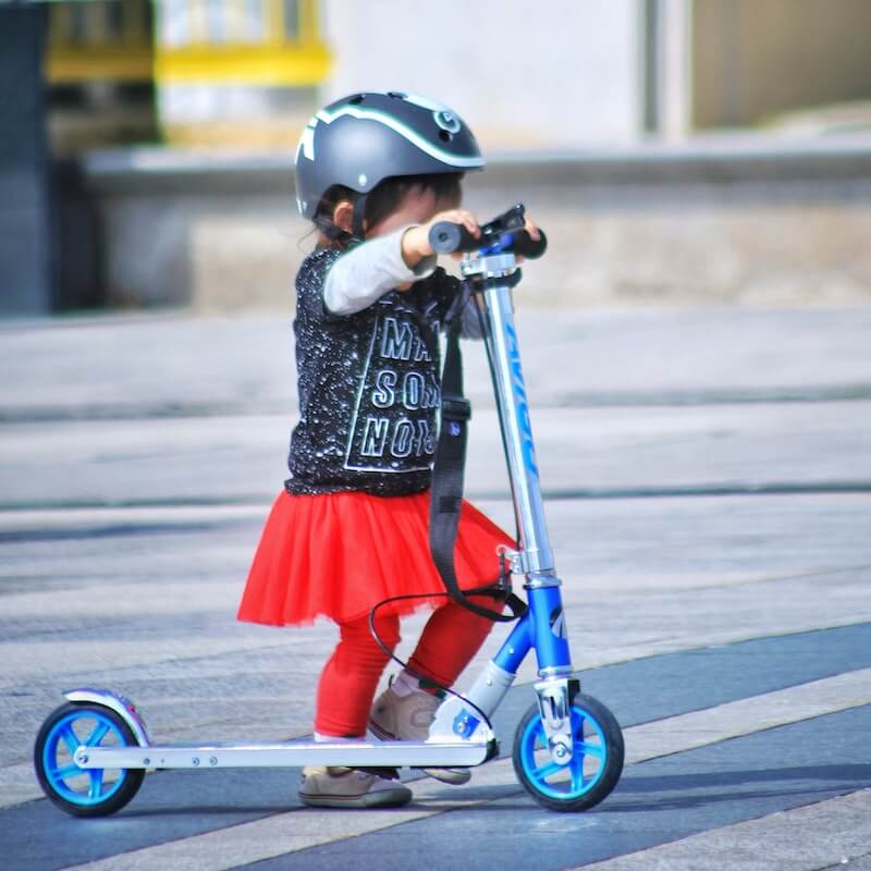 Girl with scooter helmet on scooter for kids
