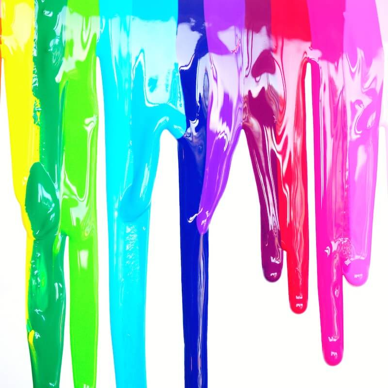 Acrylic Paint in different colours dripping down white wall